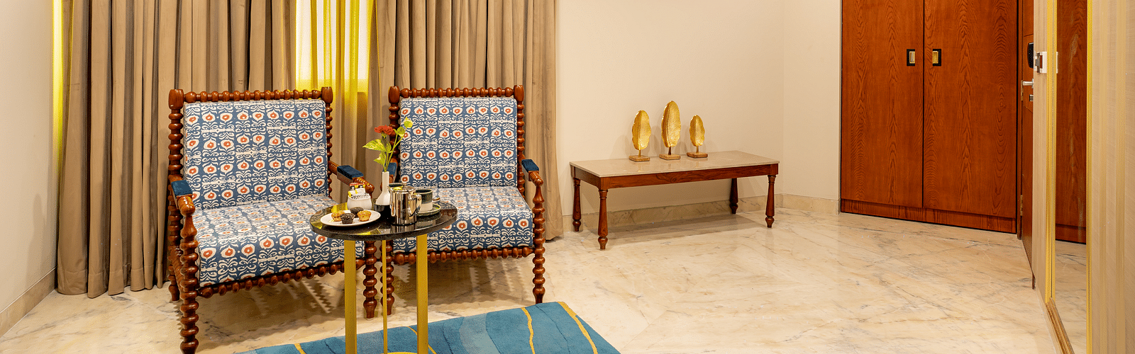 Two cushion seatingTwo cushioned seats with a wooden decorative round table and a rectangular side table in the Suite at Inde Signature Jaipur with a wooden decorative round table and side rectangle table in Suite at Inde SIgnature Jaipur