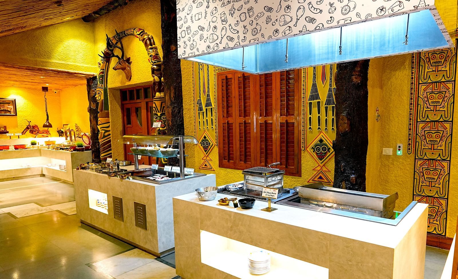 A modern buffet area with sleek service counters and decorative lighting at Tara, Comfort Hotel in Hyderabad - Ramoji Film City.