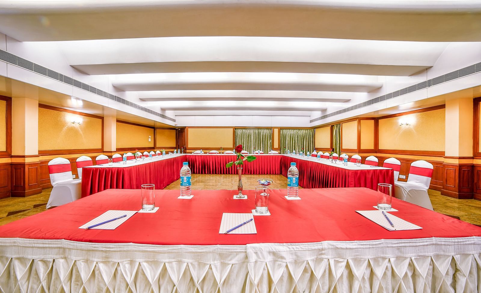 A meeting setup in a hall with a red tablecloth and a classroom-style arrangement. - Tara, Comfort Hotel in Hyderabad - Ramoji Film City.