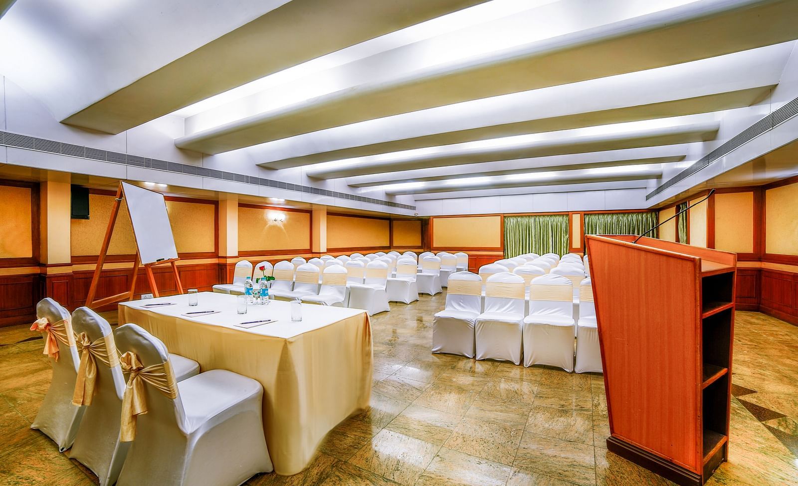 A spacious event hall with tables set in a hollow square layout and elegant lighting. - Tara, Comfort Hotel in Hyderabad - Ramoji Film City.