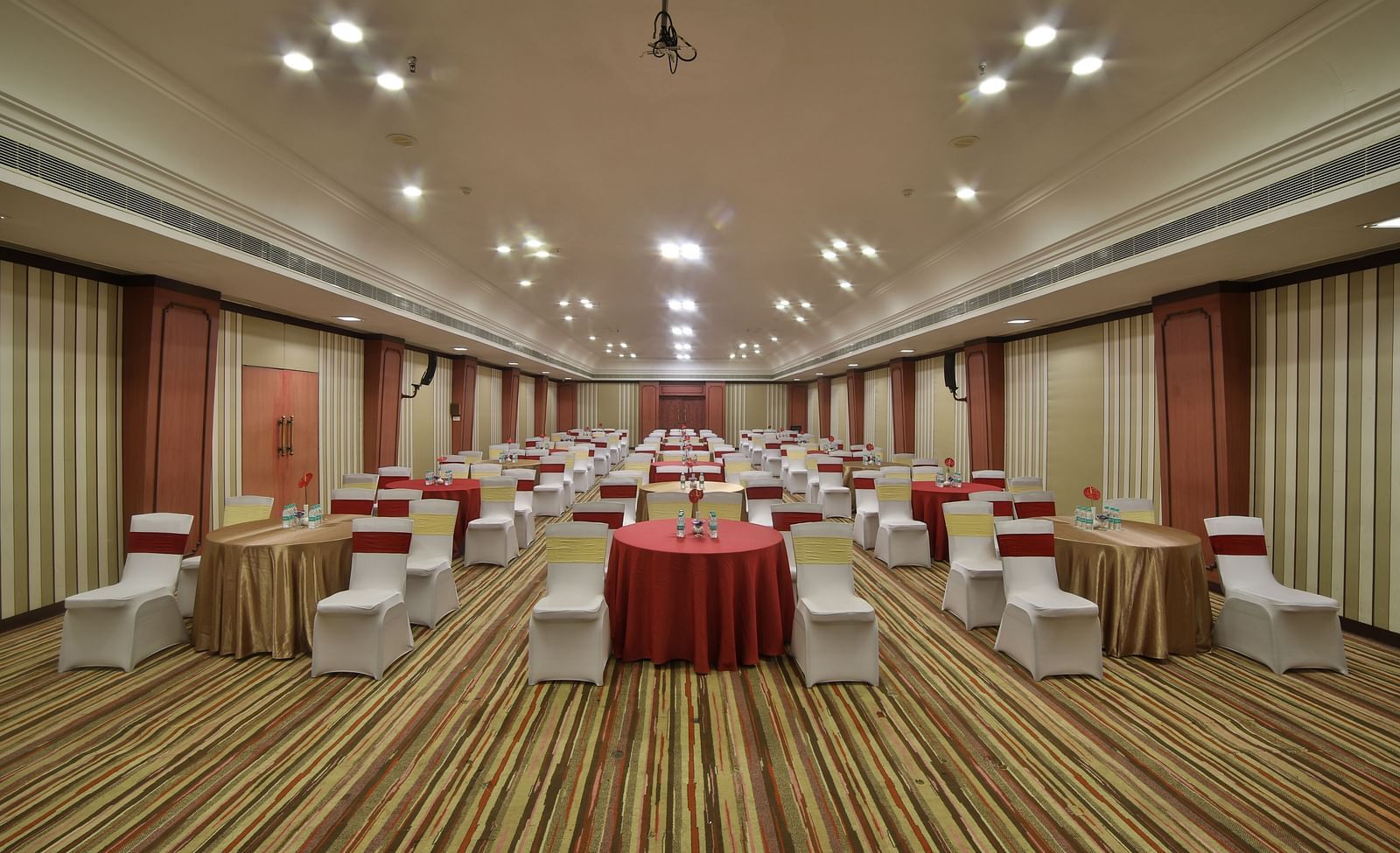  Seating arrangement in Terrace Hall A grand hotel suite with an opulent red and white decor, large bed, and seating area, reflecting a traditional style at Sitara Luxury Hotel in Hyderabad near Ramoji Film City.