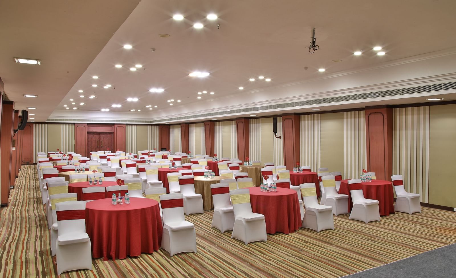  Seating arrangement in Terrace Hall A grand hotel suite with an opulent red and white decor, large bed, and seating area, reflecting a traditional style at Sitara Luxury Hotel in Hyderabad near Ramoji Film City.