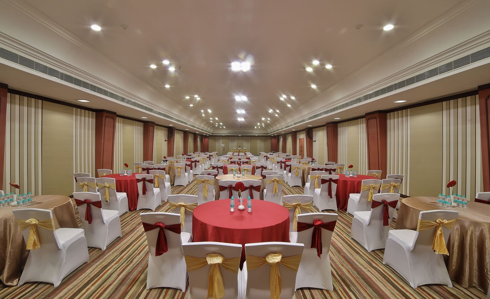  Seating arrangement in Terrace Hall A grand hotel suite with an opulent red and white decor, large bed, and seating area, reflecting a traditional style at Sitara Luxury Hotel in Hyderabad near Ramoji Film City.