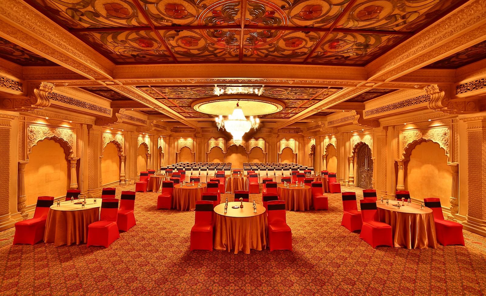 Seating arrangement in Taj Mahal Hall A grand hotel suite with an opulent red and white decor, large bed, and seating area, reflecting a traditional style at Sitara Luxury Hotel in Hyderabad near Ramoji Film City.