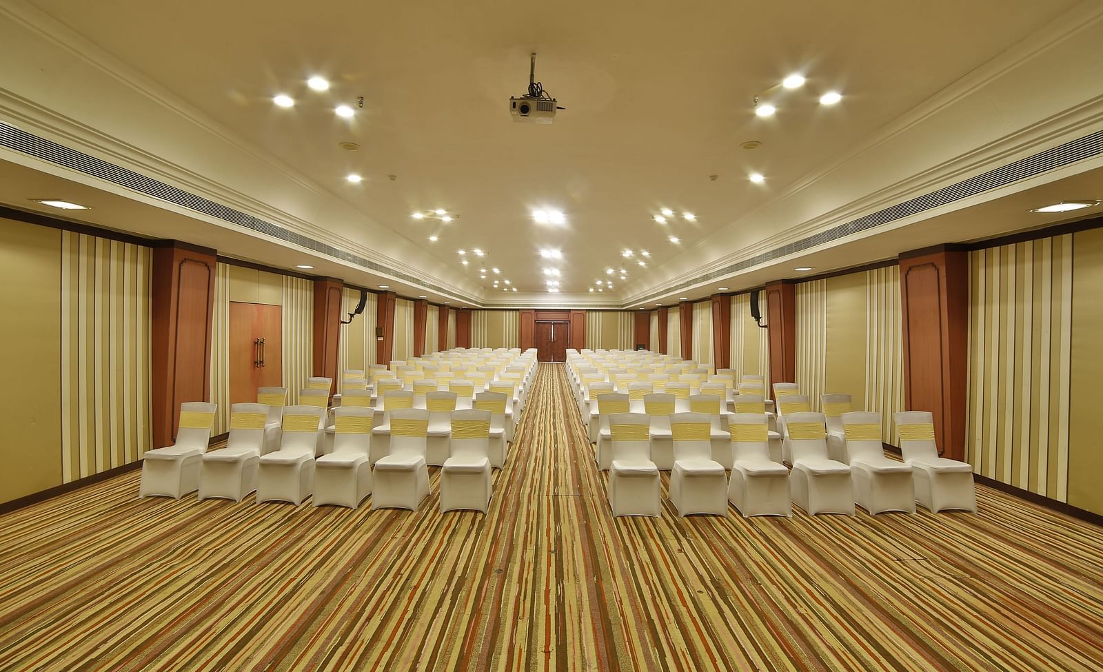  Seating arrangement in Terrace Hall A grand hotel suite with an opulent red and white decor, large bed, and seating area, reflecting a traditional style at Sitara Luxury Hotel in Hyderabad near Ramoji Film City.