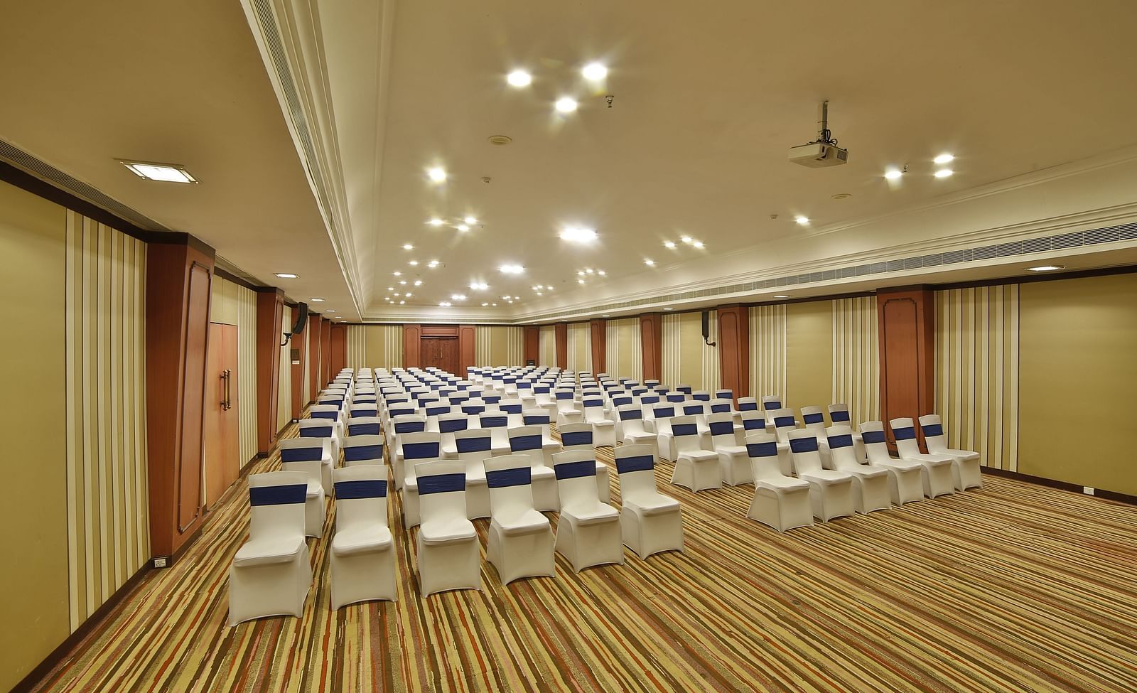   Seating arrangement in Terrace Hall A grand hotel suite with an opulent red and white decor, large bed, and seating area, reflecting a traditional style at Sitara Luxury Hotel in Hyderabad near Ramoji Film City.