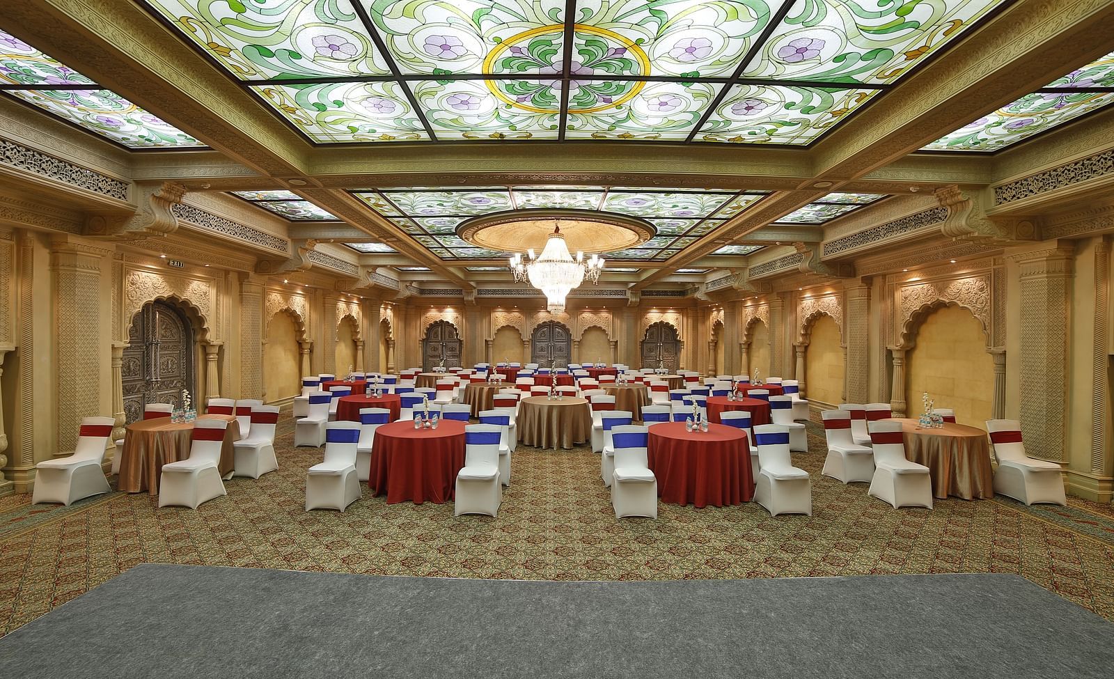  Seating arrangement in Taj Mahal Hall A grand hotel suite with an opulent red and white decor, large bed, and seating area, reflecting a traditional style at Sitara Luxury Hotel in Hyderabad near Ramoji Film City.