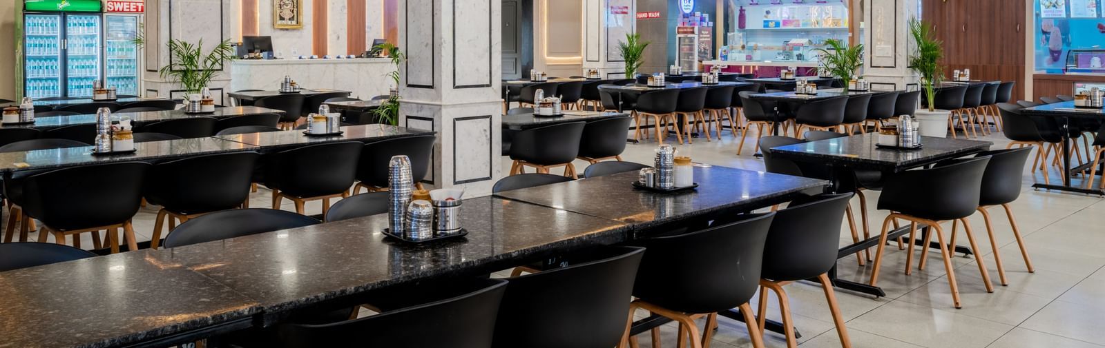 Modern restaurant with neatly arranged seating and elegant ceiling lights at Hotel Highway King, Neemrana.
