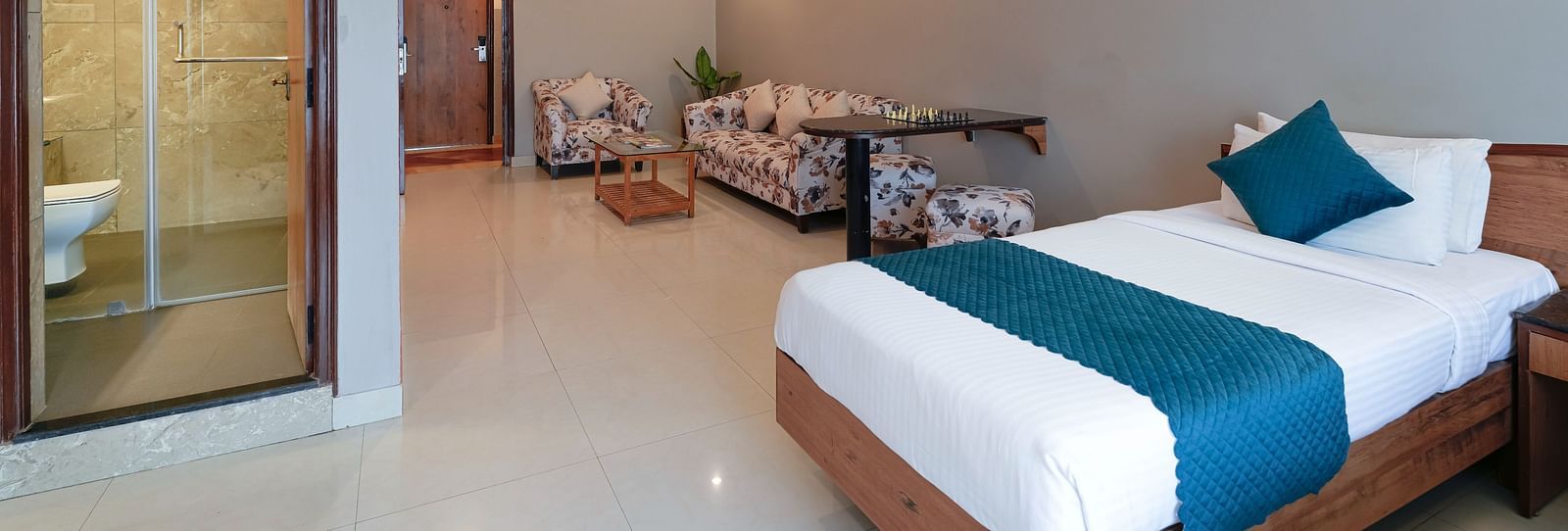  A hotel room in Bengaluru with a queen size bed, modern amenities, and a glass-partitioned bathroom - Cross Roads Inn, Bengaluru