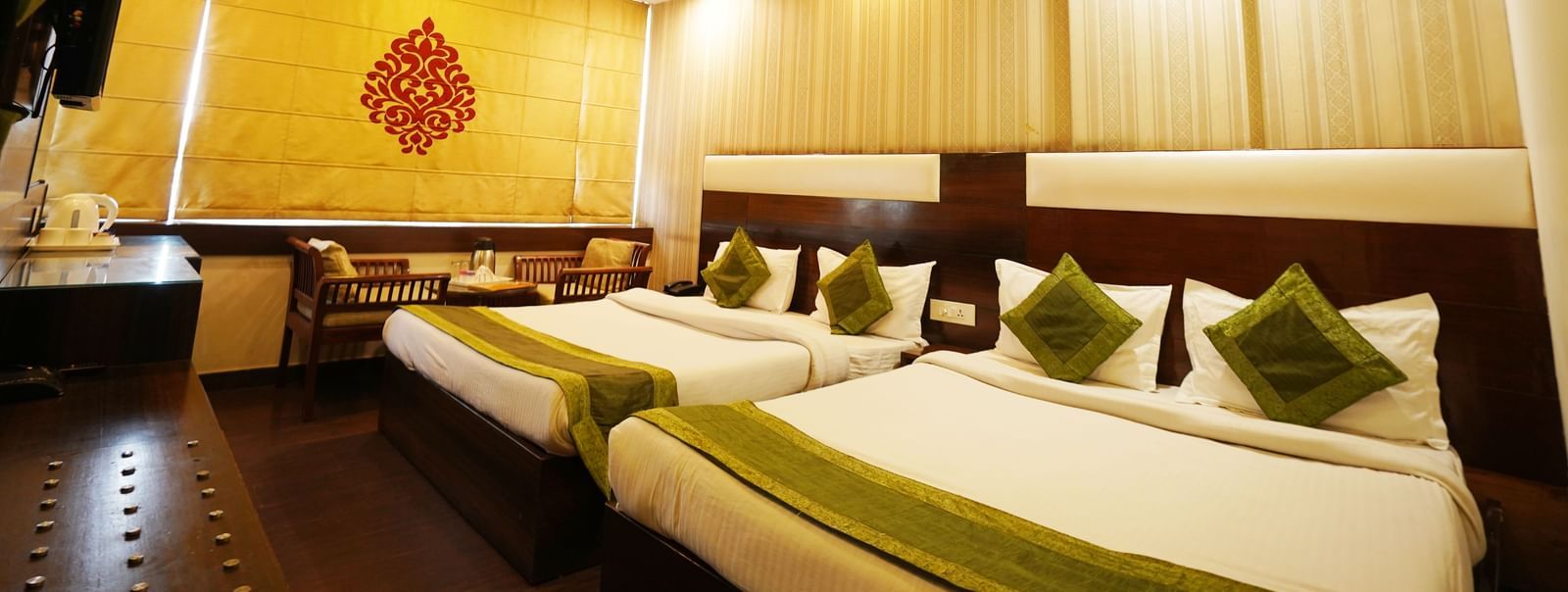 A long view of Family room at Hotel Dreamland, Chandigarh with two King-sized beds with cushions and pillows, curtains rolled down, AC and a designed ceiling with fan. 