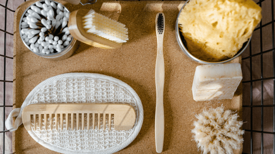A top-down view showing toiletries including a wooden comb, a toothbrush, cotton swabs, and sponges neatly arranged in a tray.