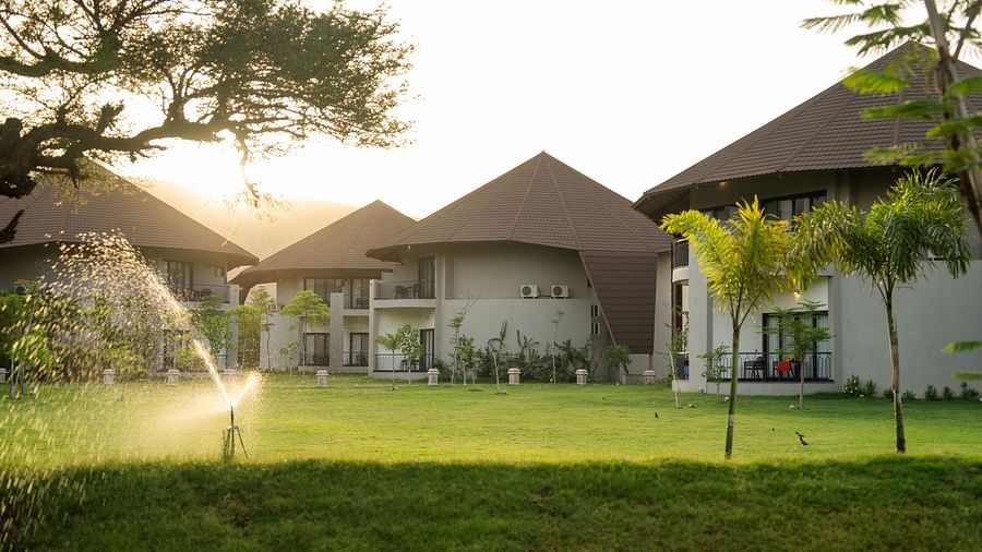 Lush green lawn with water sprinklers and scenic villas in the background at Ananta Spa and Resort, Ajabgarh.