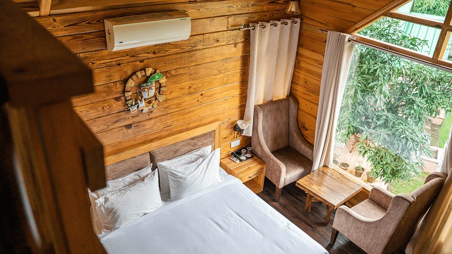A view of the large bed alongside chairs placed near a large bed at Pinewood Cottage at the Sylvan Retreat, Dehradun.