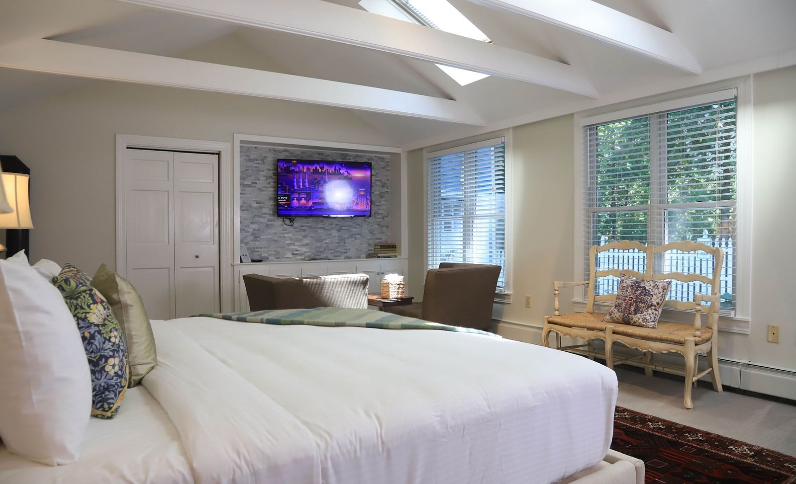 Hotel room with white bed, TV, and large windows at Hartstone Inn