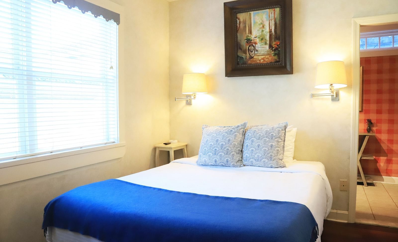 Bedroom with a blue throw, white bedding, and framed art at Hartstone Inn.