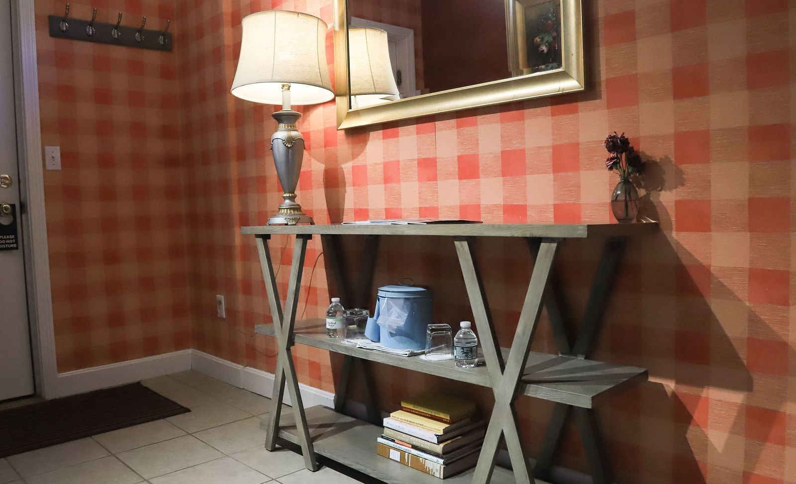 Room with checked wallpaper, a mirror on the wall, and lamp on the table at Hartstone Inn.