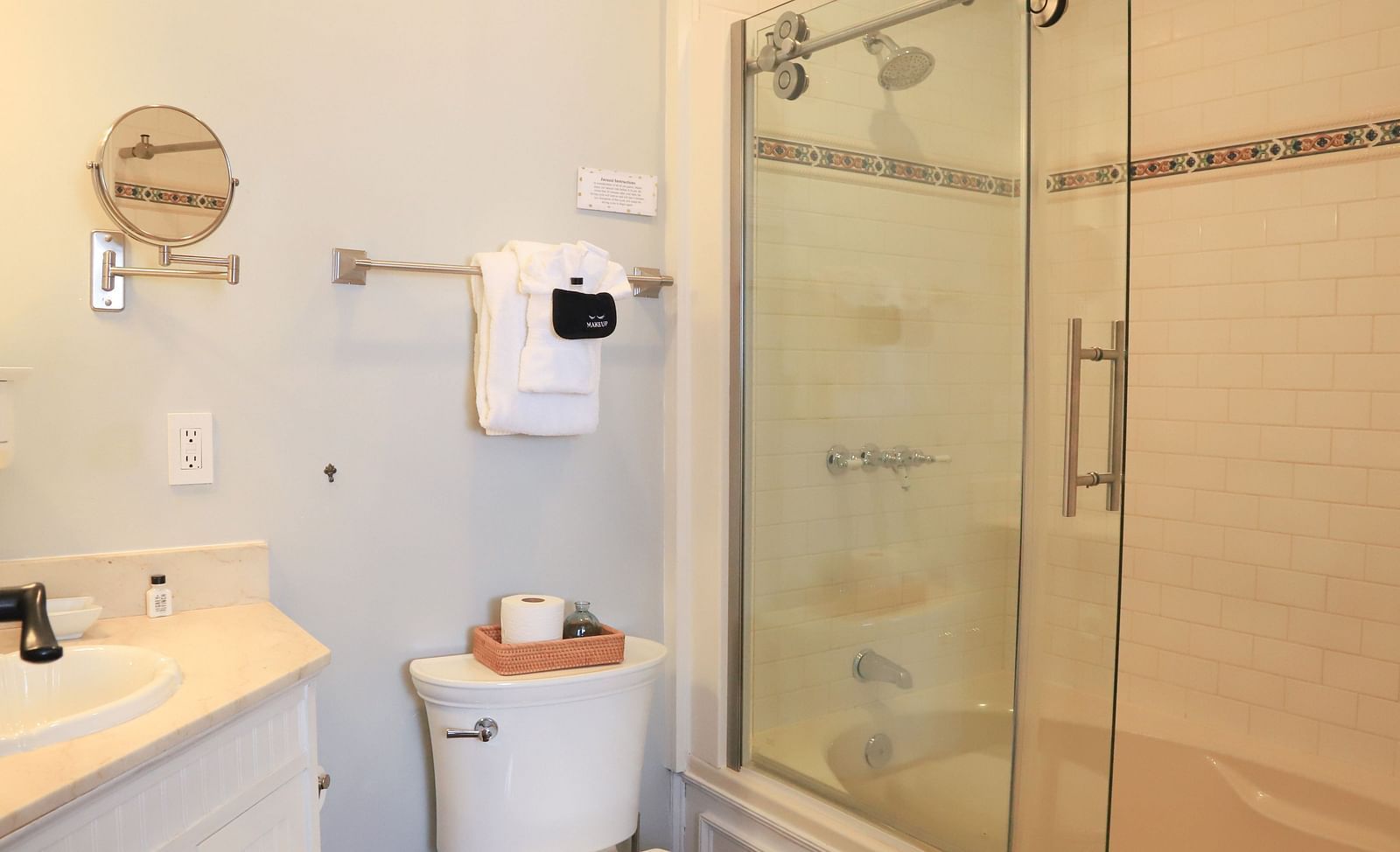 Bathroom with glass-walled shower area, small mirror, sink, and tissue roll placed near the toilet area at Hartstone Inn.