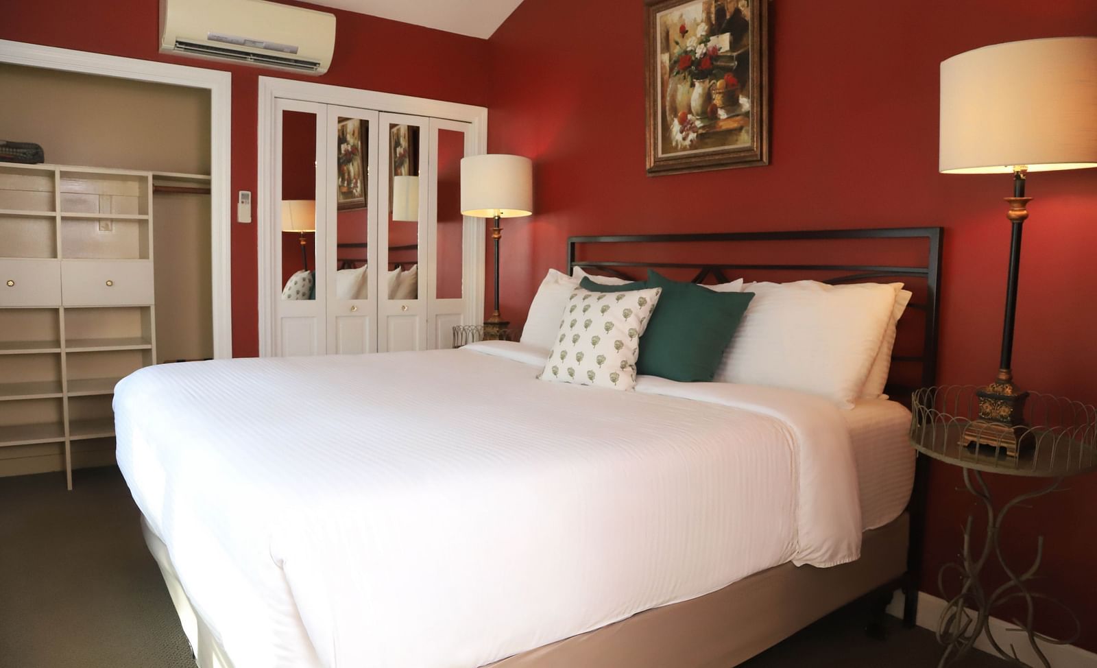 Hotel room with red walls, bed, and a lamp beside the bed at Hartstone Inn.