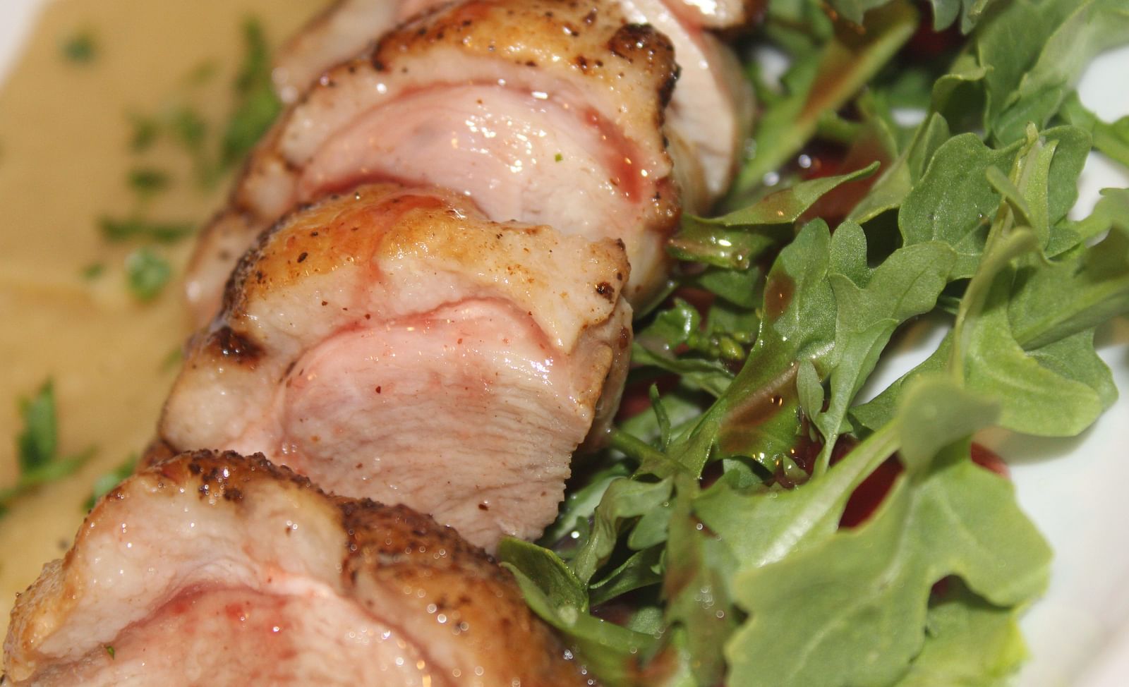 Sliced roasted meat served on greens with a creamy sauce.