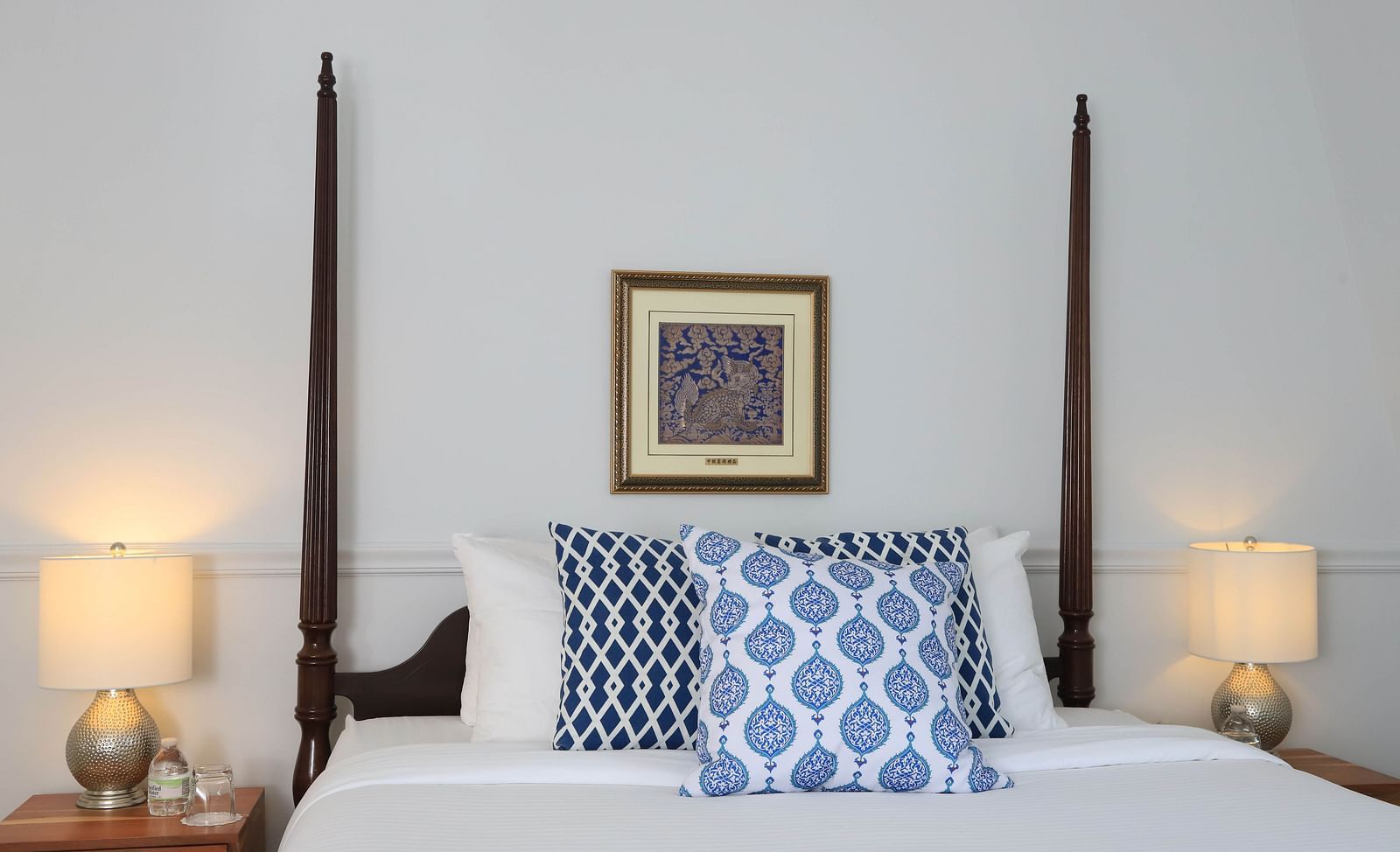 Queen bed with blue accent pillows and framed artwork at Hartstone Inn.