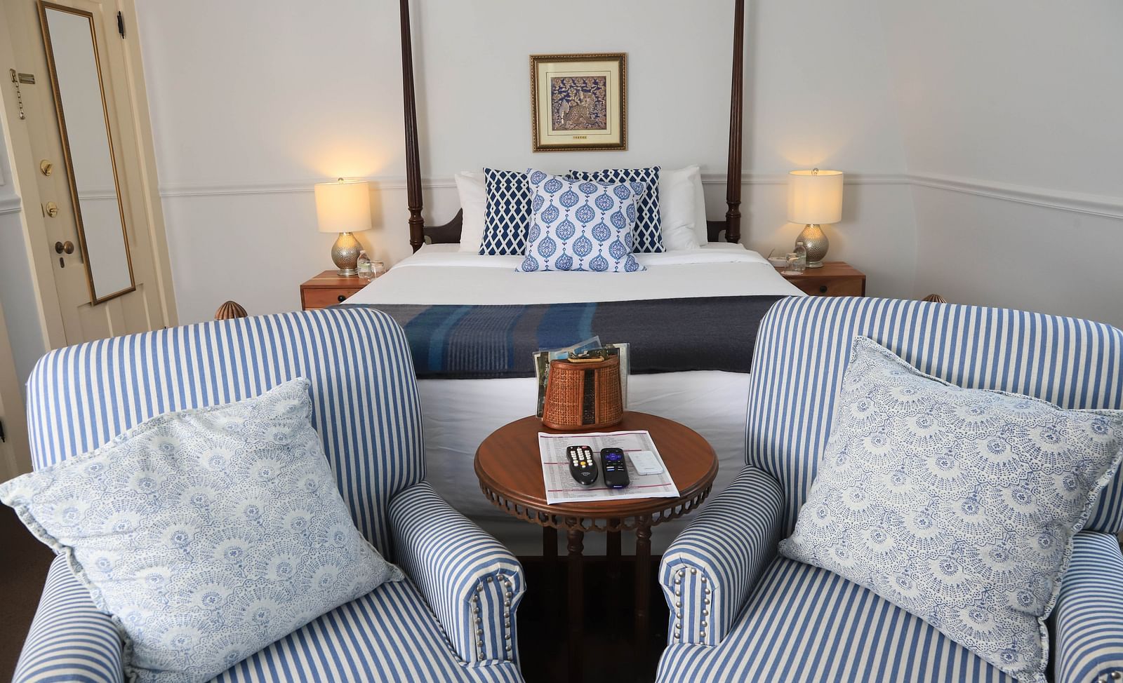 Seating area with striped chairs, tray table and showcasing a king size bed in the background at Hartstone Inn
