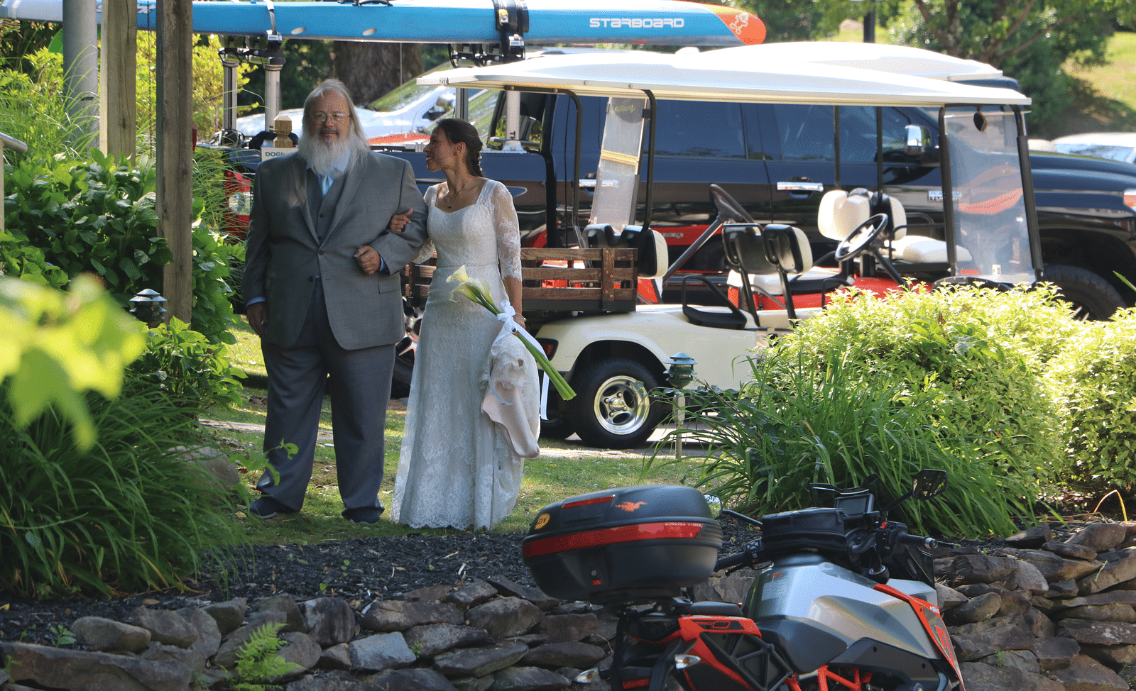 a father along with his daughter dressing in a white wedding gown and a golf cart behind them - Historic Tapoco Lodge