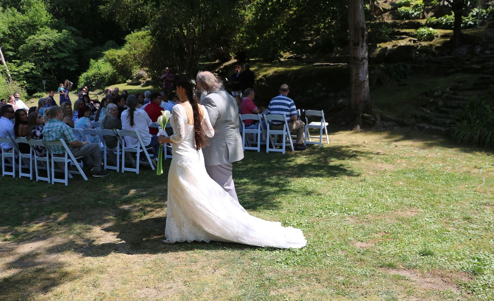a bright image of a father walking along with the bride as they walk down the lawn - Historic Tapoco Lodge