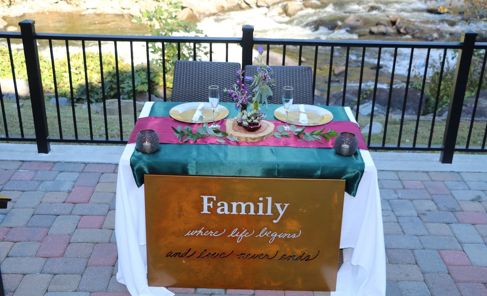 a table featuring a copper signage reading family with two plates set on the table and the beautiful river views in the background - Historic Tapoco Lodge