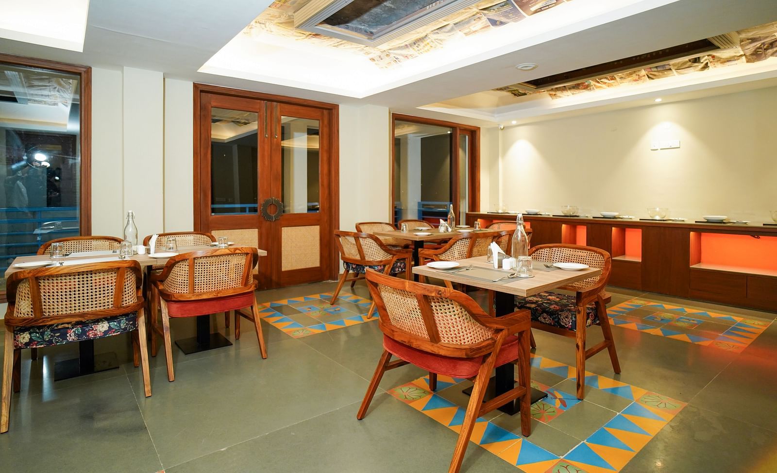 A dining area with multiple tables and chairs, featuring wooden accents and a patterned ceiling | Sukama Resort & Spa, Nainital