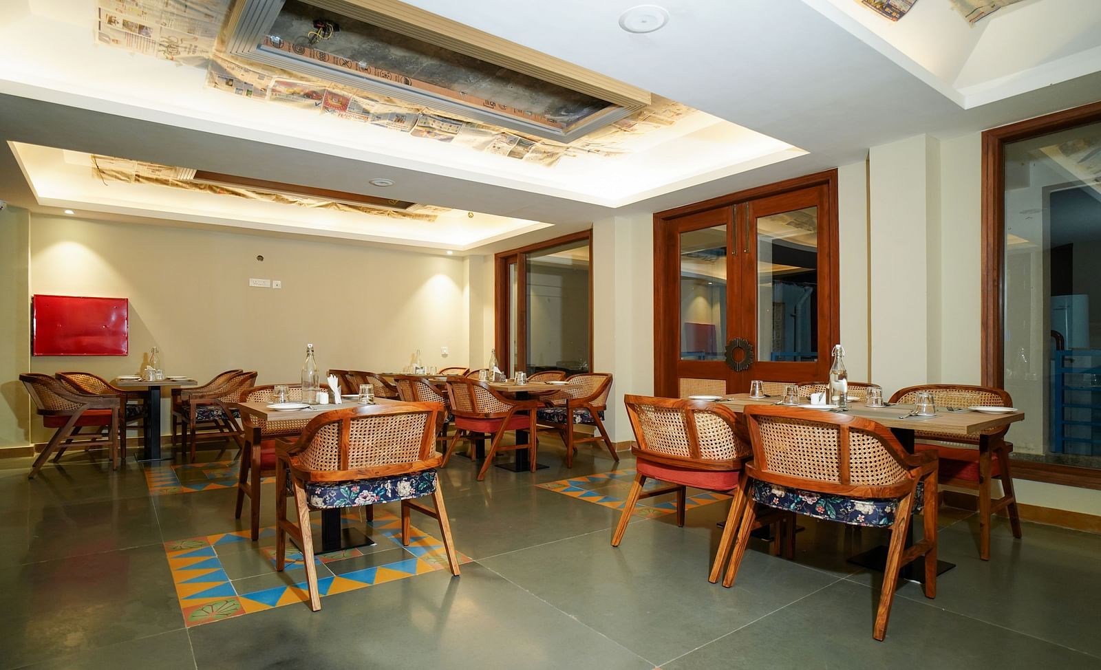 A spacious dining area with wooden tables and chairs, illuminated by overhead lighting and natural light from large windows | Sukama Resort & Spa, Nainital