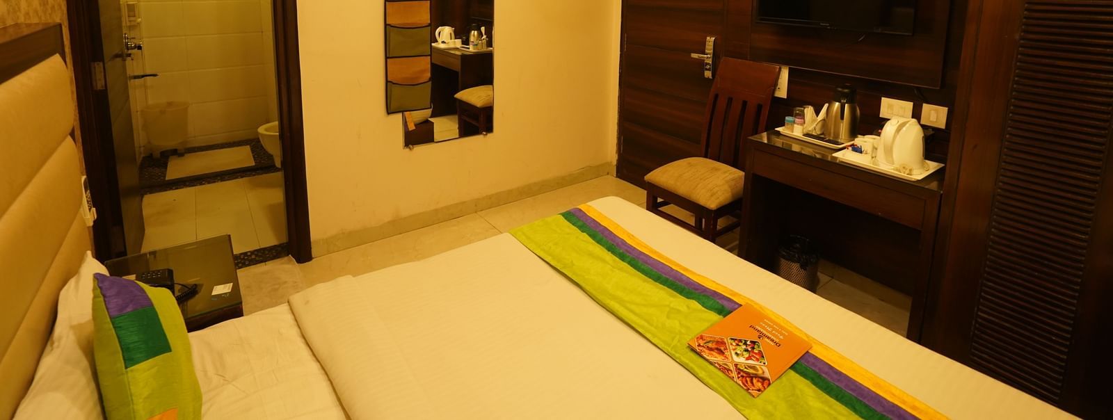 Standard Room at Hotel Dreamland, Chandigarh with king-size bed, bedside table, TV, single chair and private bathroom. 