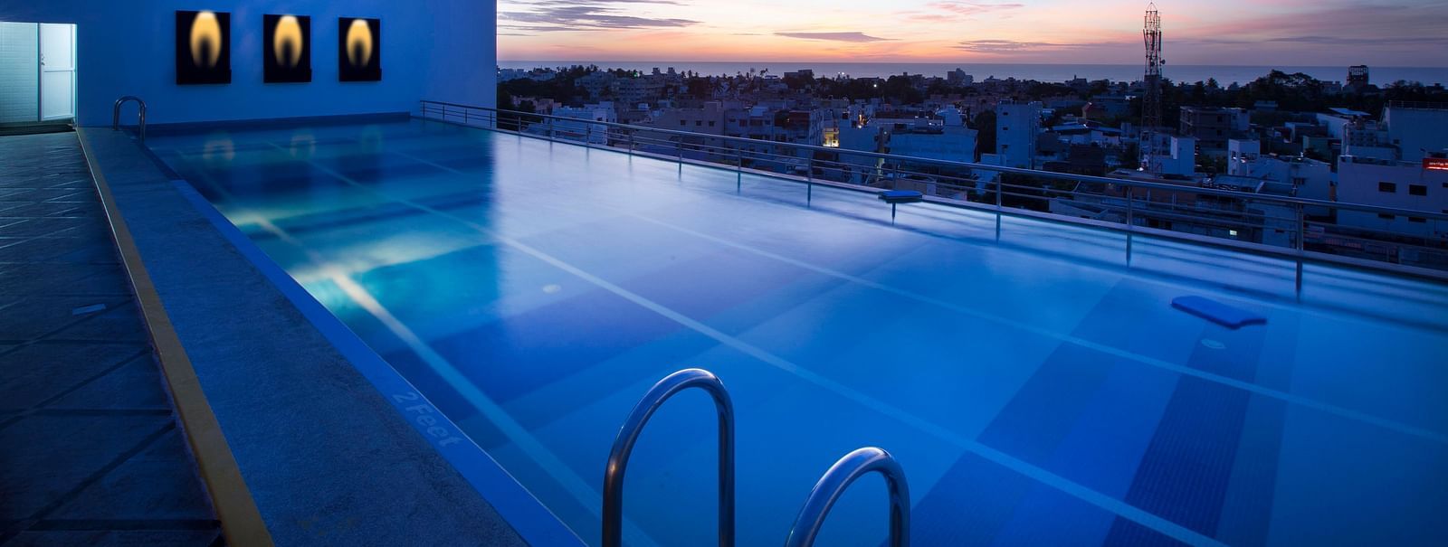 view of a swimming pool at sunset at Hotel Atithi - TGI Grand, Pondicherry
