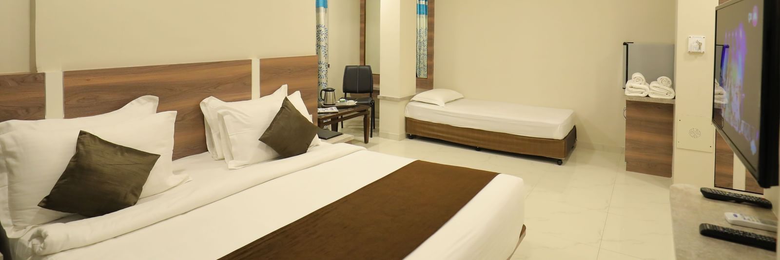 Close up of the king size bed and single bed in the Suite of Highland Resort, facing a wall-mounted TV.