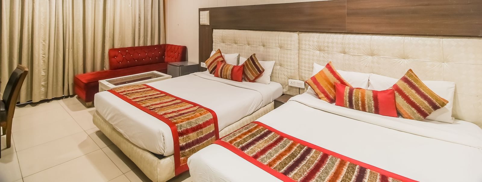Twin beds with side tables and seating zone at Hotel Diamond Plaza, Chandigarh