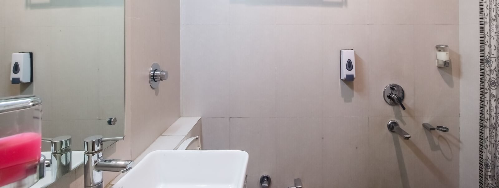 Bathroom with a sleek sink, a mirror, and shower area in the Club Room - Hotel Diamond Plaza, Chandigarh.