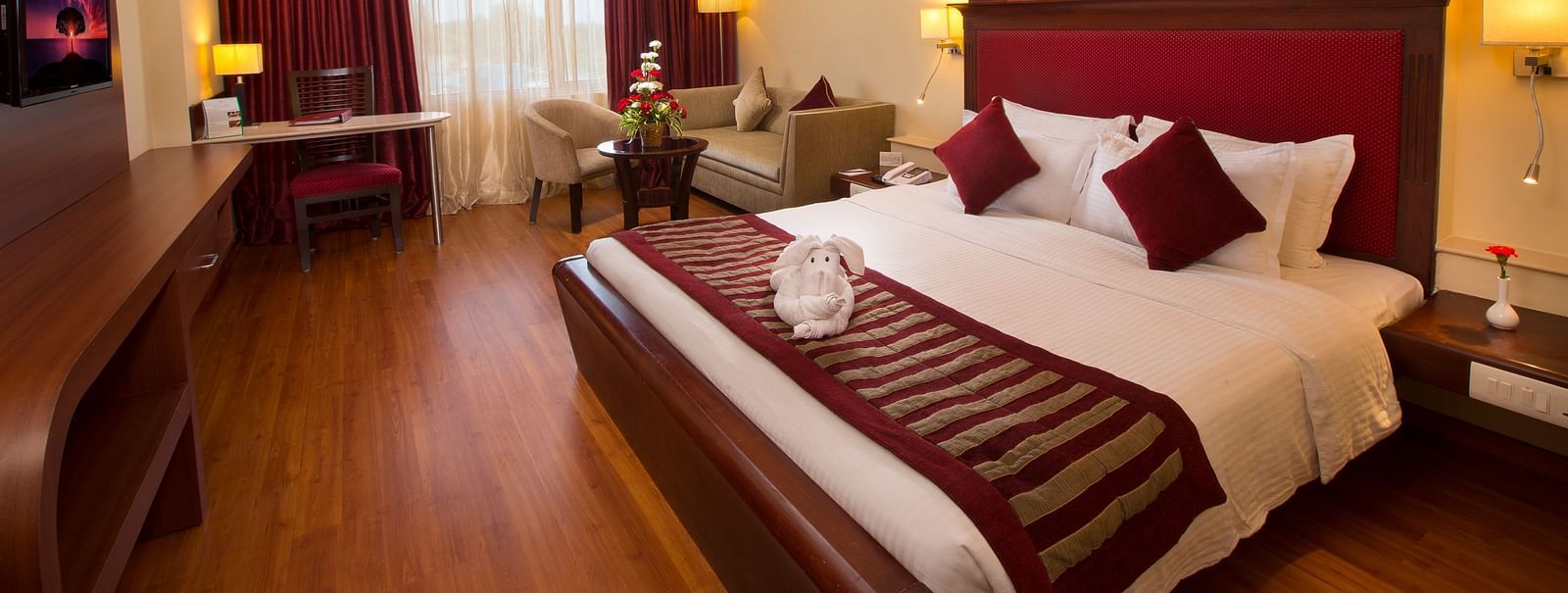 A well-appointed room with a comfortable bed, seating areas, a TV, and lamps.