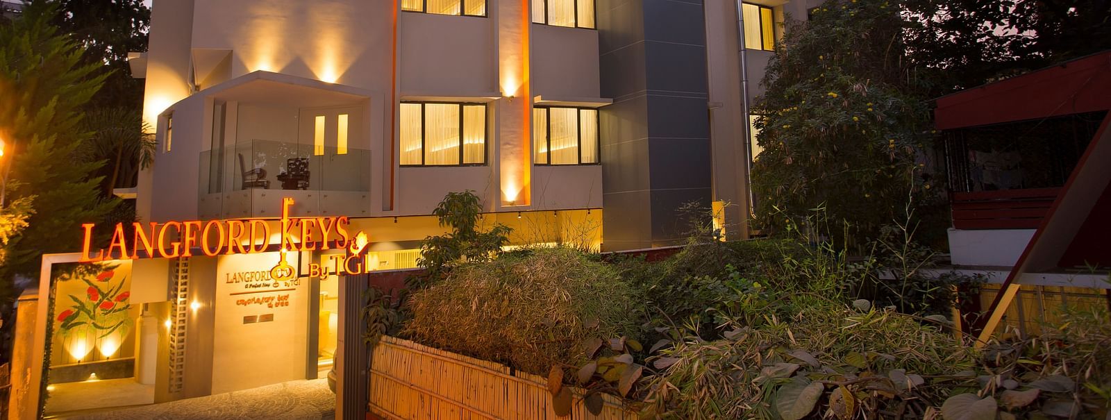 The exterior entrance of Langford Keys Hotel showing the signboard with reflective windows and modern architecture at dusk - Hotel Langford Keys by TGI, Shanti Nagar