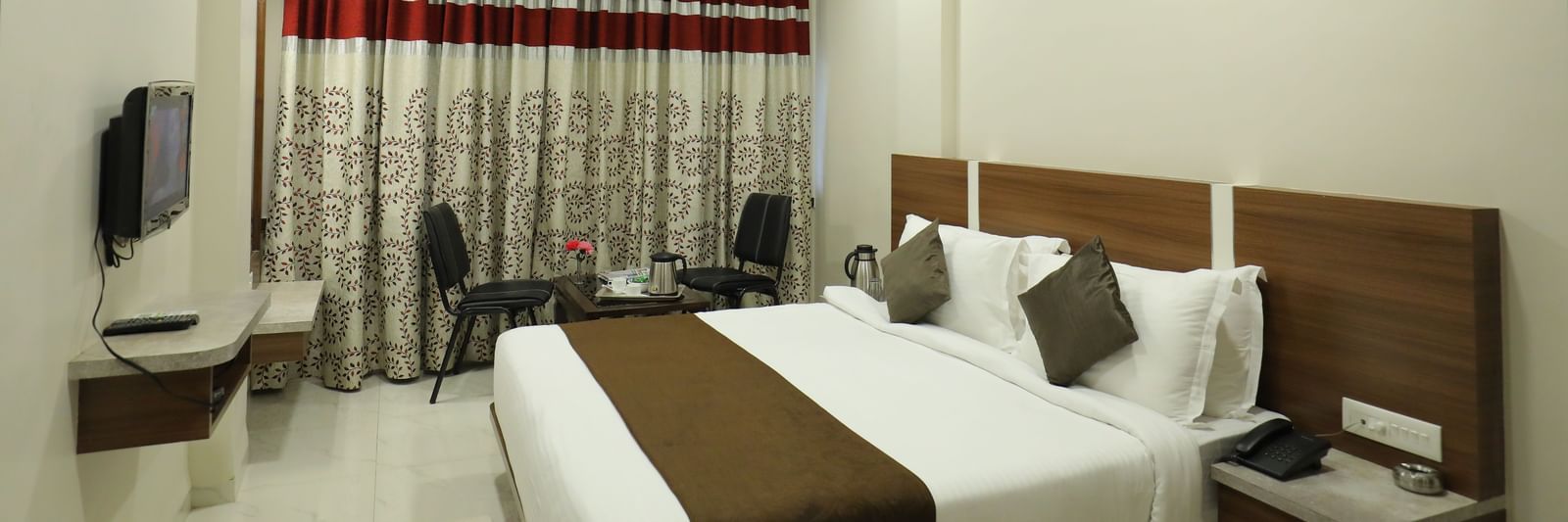 The Deluxe Room at Highland Resort features a queen size bed, a seating area for two, air-conditioning, and a wall-mounted TV.