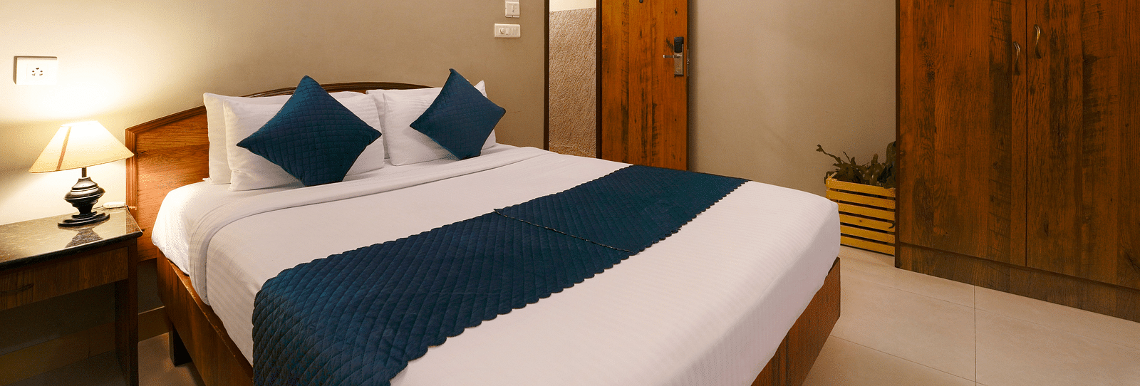 A Deluxe Room with a queen size bed, minimalist design, and modern amenities - Cross Roads Inn, Bengaluru