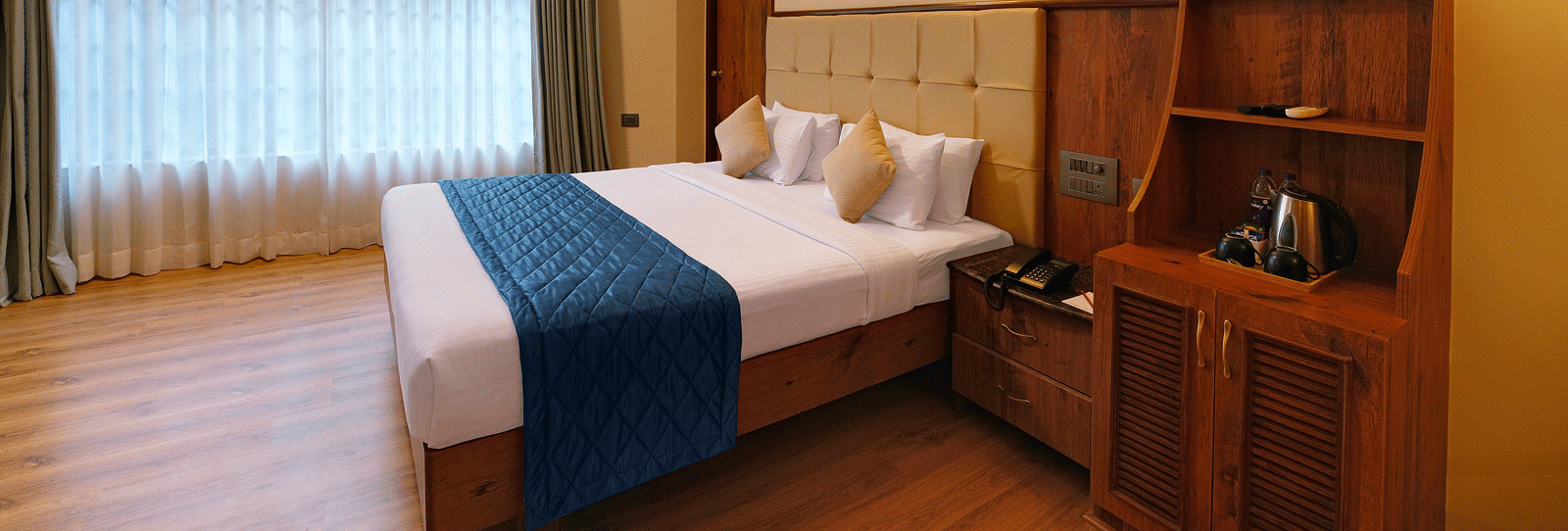 A room in bengaluru with large windows, a queen size bed, and wooden decor - Cross Roads Inn, Bengaluru