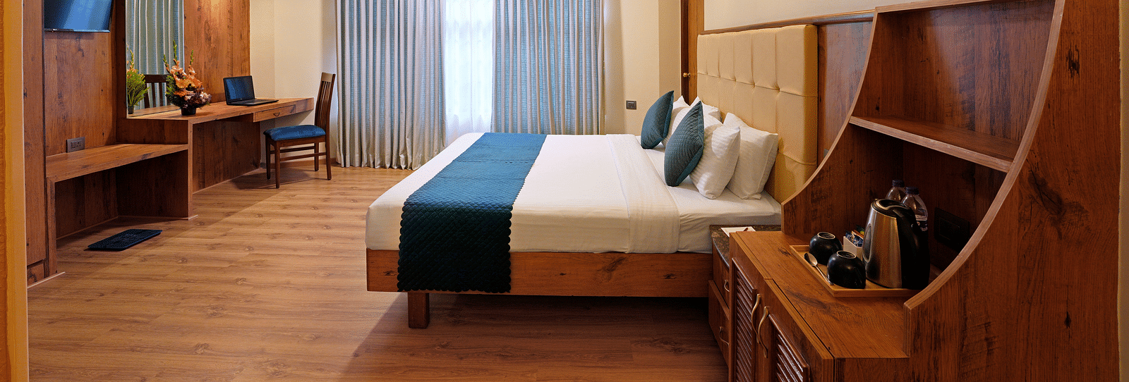 An Executive Room featuring a queen size bed, wooden decor and large windows - Cross Roads Inn, Bengaluru