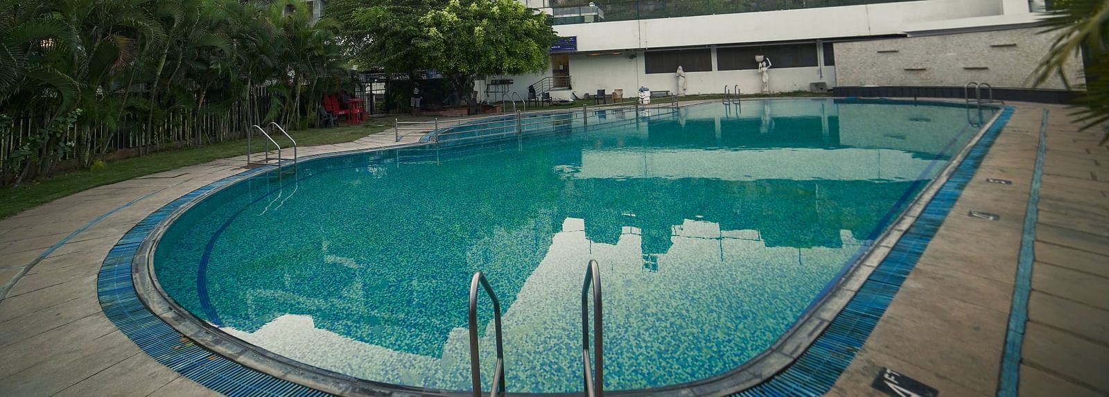An outdoor swimming pool with blue water and surrounding buildings, part of BNGV Grandeur Hotel and Banquets.