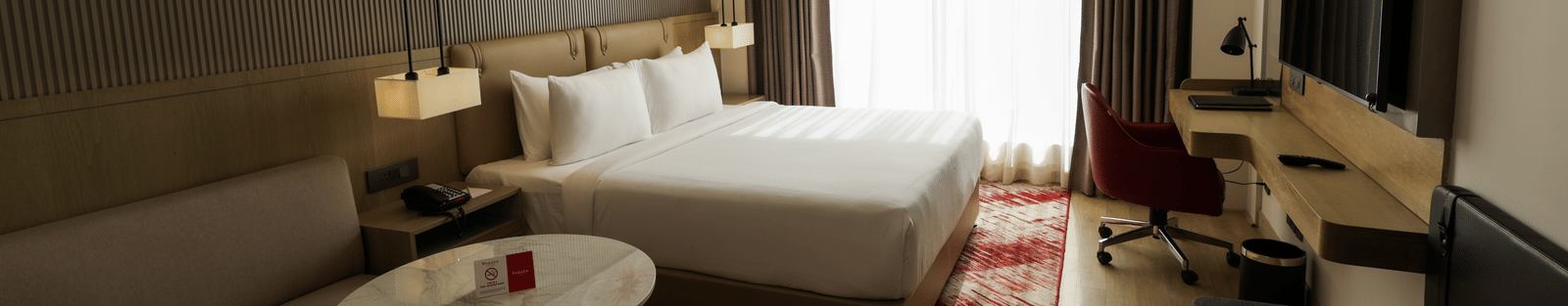 Room with seating area and a bed, offering ample natural light at Ramada by Wyndham Sonipat Murthal