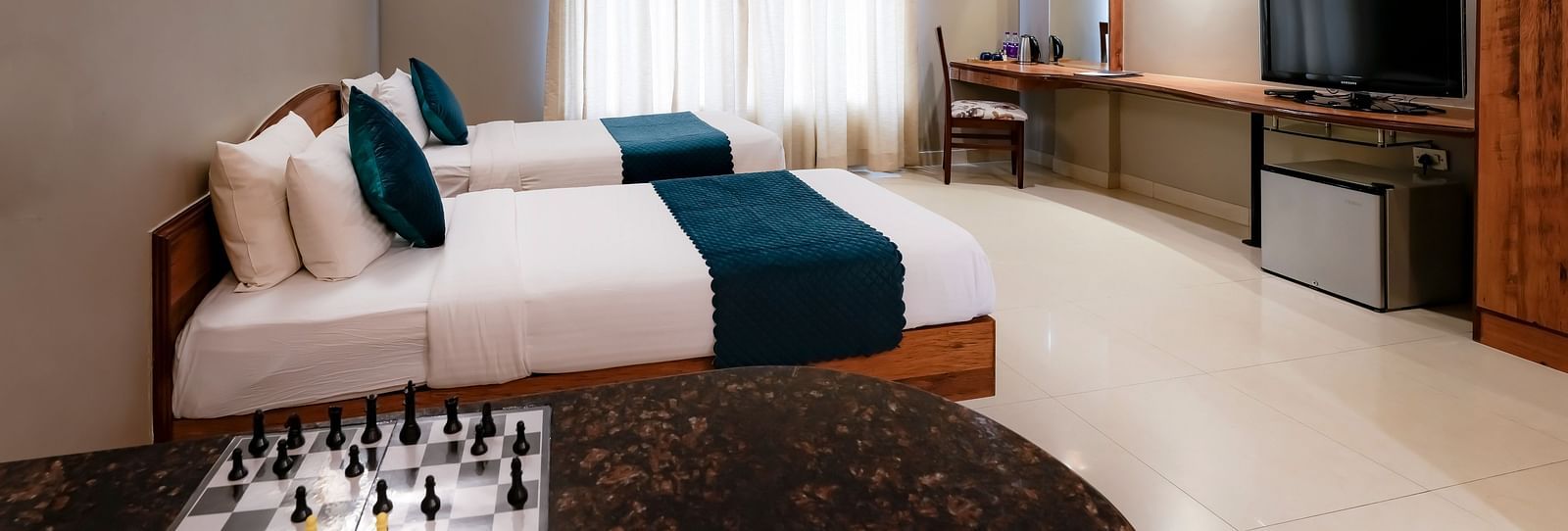An Executive Room with twin beds, a desk with a chessboard, and stylish decor - Cross Roads Inn, Bengaluru