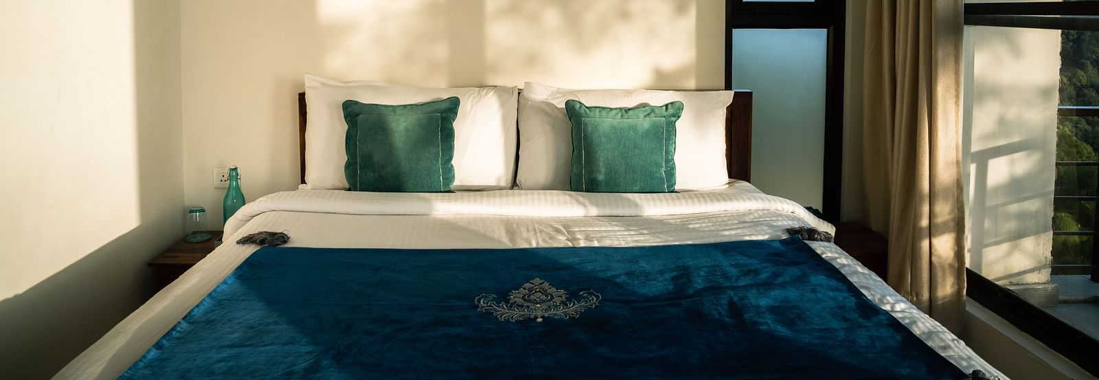 A bedroom with sunlight streaming through the windows at BluSalzz Escapade Resort, Lansdowne.