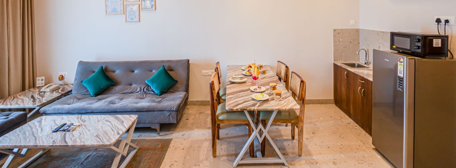Living area at Sajjan Villa featuring a sofa set with centre table and a dining table with chairs. The room also features a refrigerator,  oven, a sink.