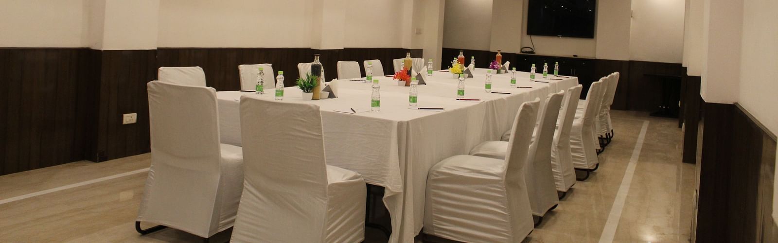 An image of a conference hall featuring a a large table at the centre surrounded by several chairs at Inde Hotels Vista Woods