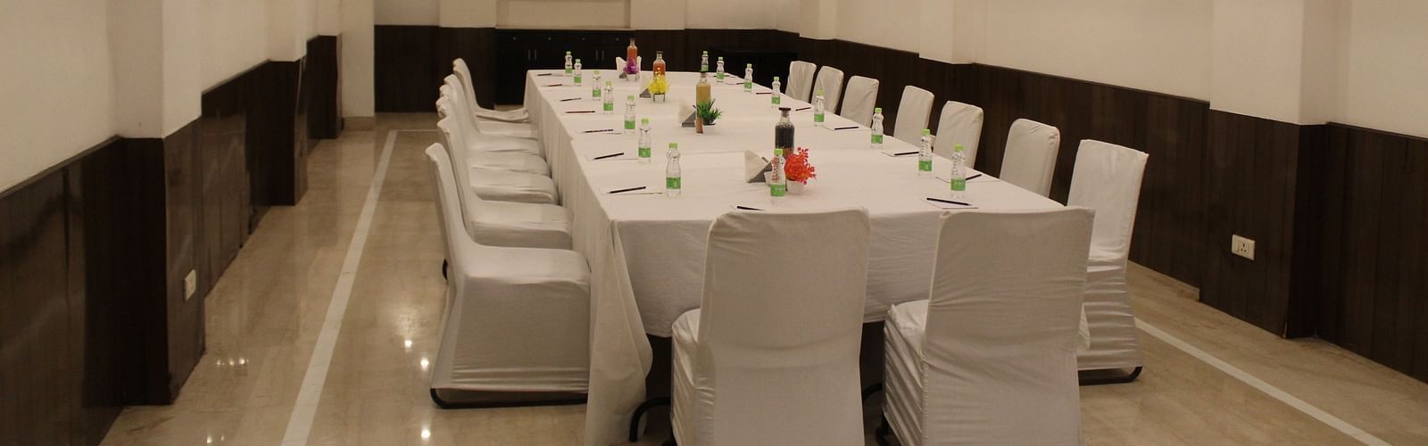 An image of a conference room at Inde Hotels Vista Woods featuring a huge table surrounded by several chairs