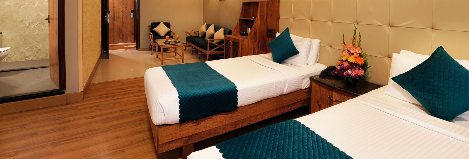  An Executive Room with cosy twin beds, a couch, and a glass-partitioned bathroom - Cross Roads Inn, Bengaluru