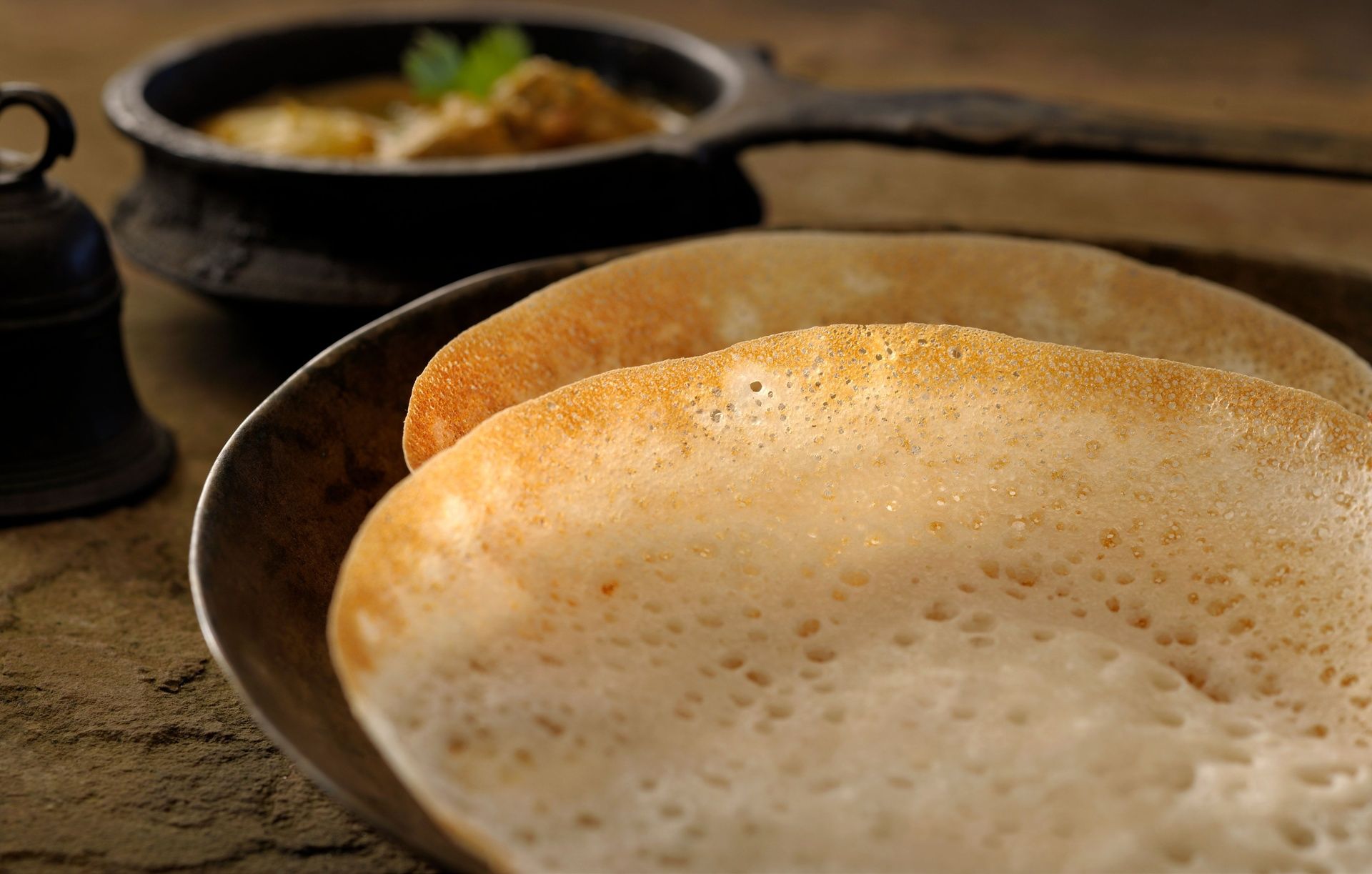 Fluffy appam and curry in a traditional pot